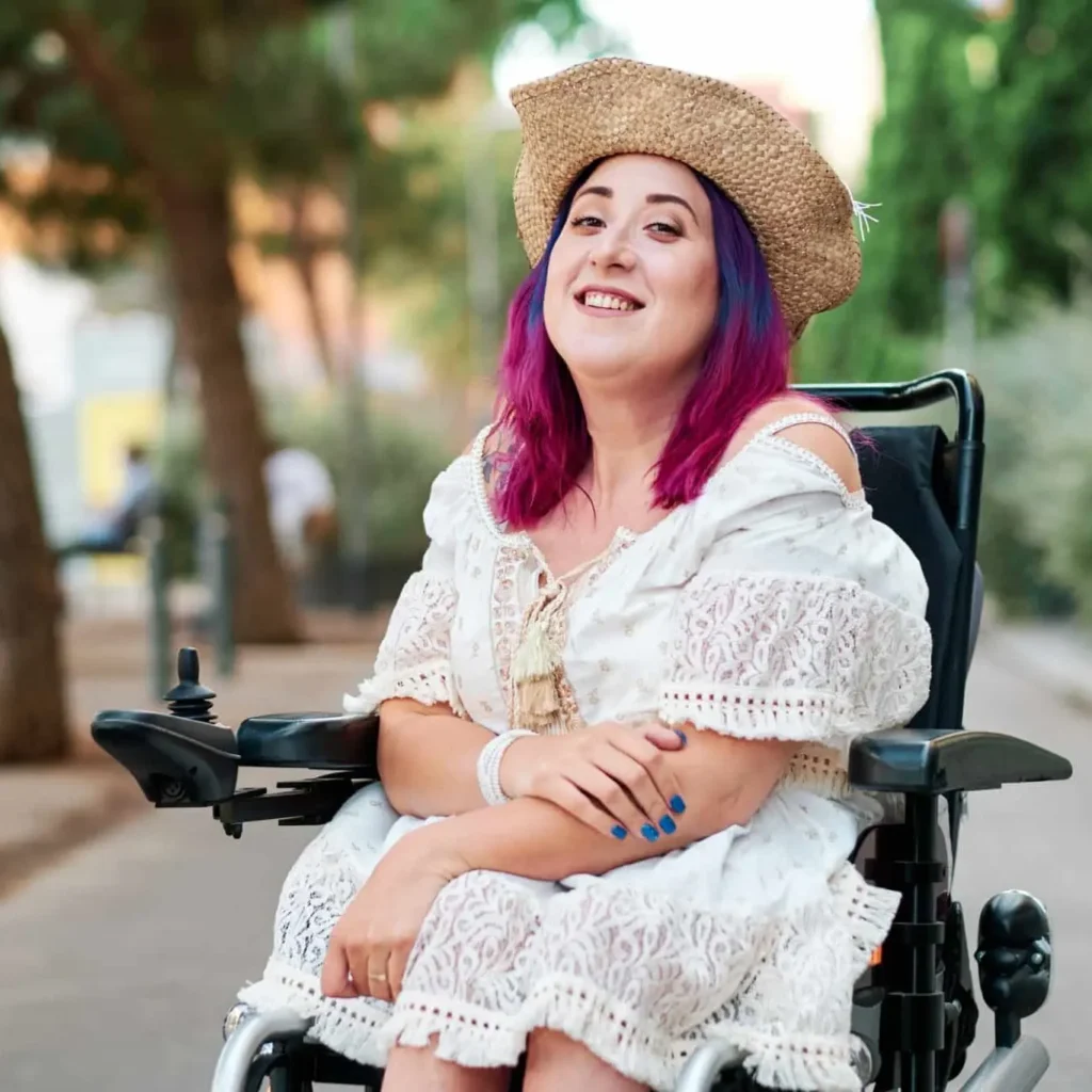 photo of young individual with ALS. They are vibrant with purple and magenta hair and blue nails